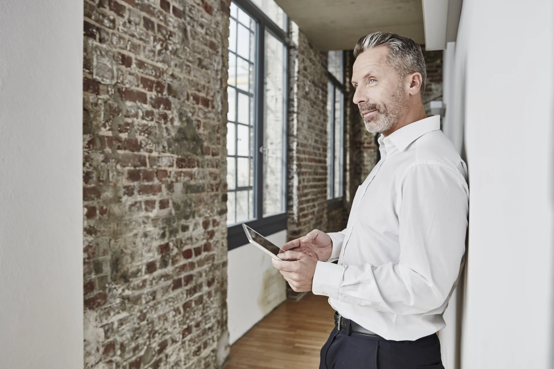 Mann hält ein Tablet und blickt konzentriert auf den Bildschirm – Sinnbild für digitales Risikomanagement und Beteiligungsmanagement mit xpecto Software im Bereich Sachwerte und Real Assets.